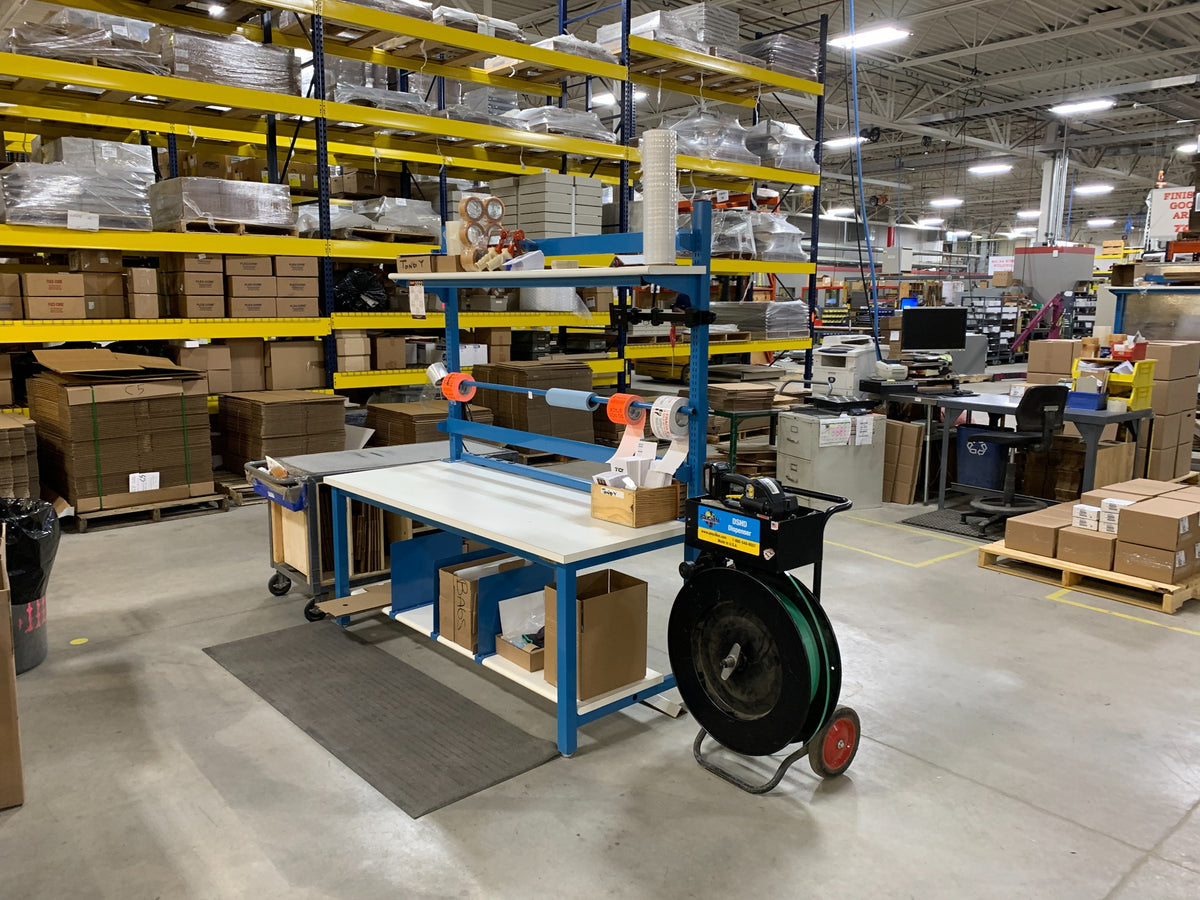 Blue packing workstation with shipping supplies and cartons in a warehouse