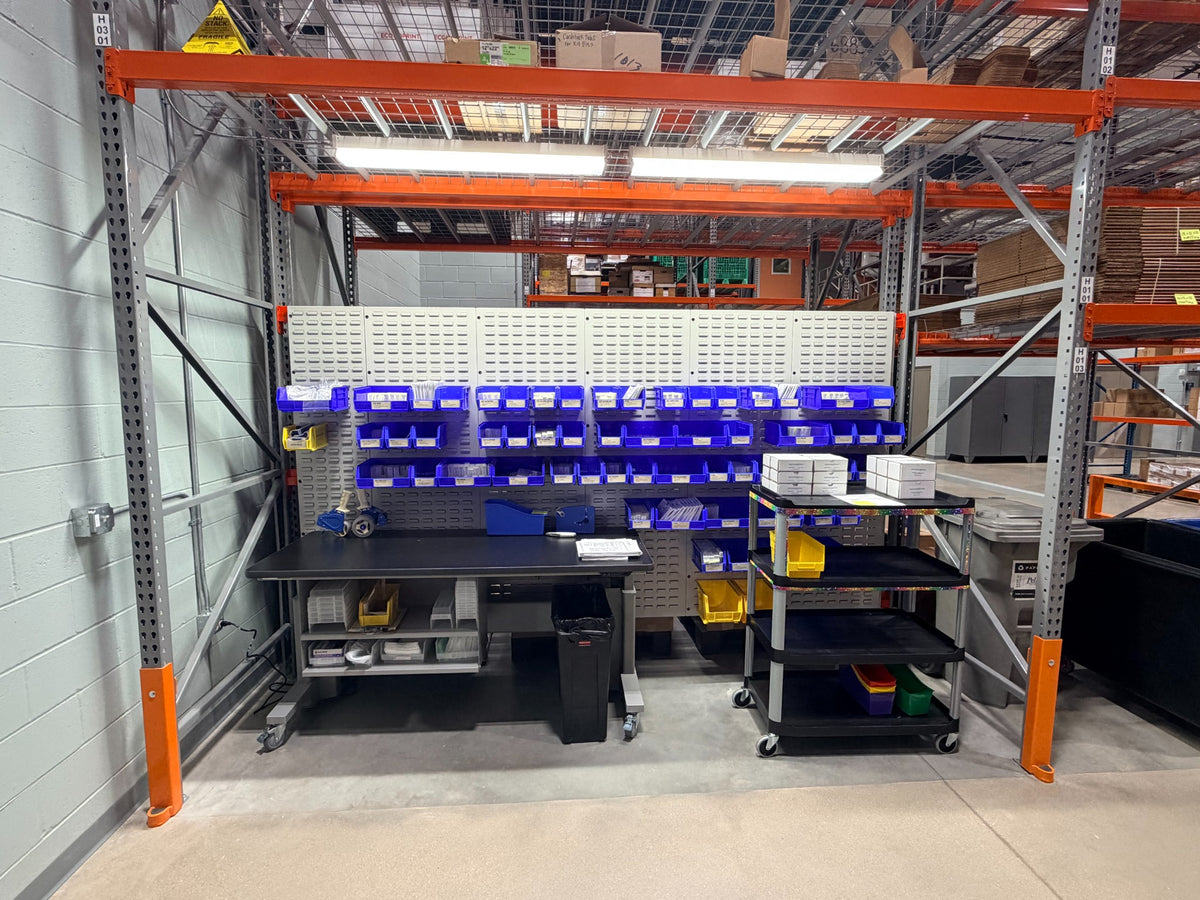 Industrial work table with organized blue parts bins in a warehouse