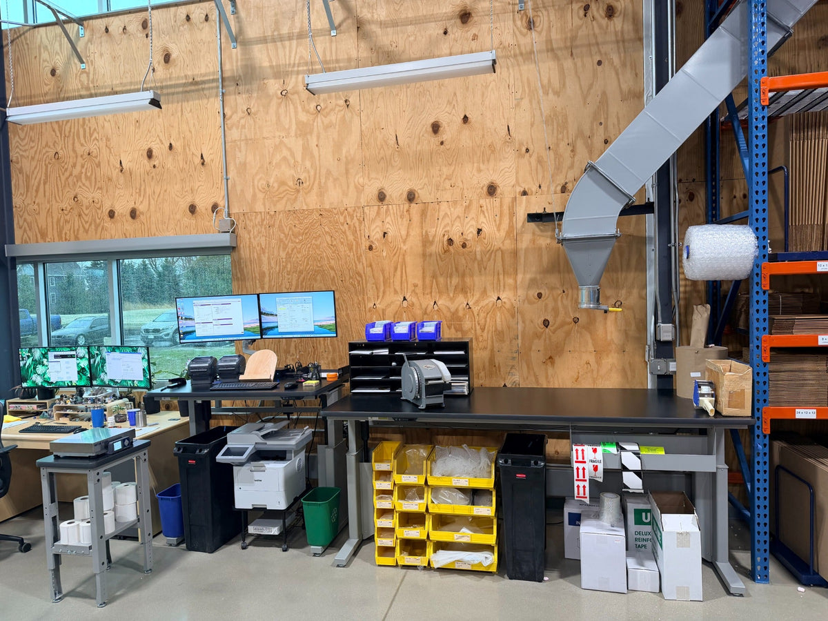 Long warehouse pack station with printers, screens, storage bins and packing supplies